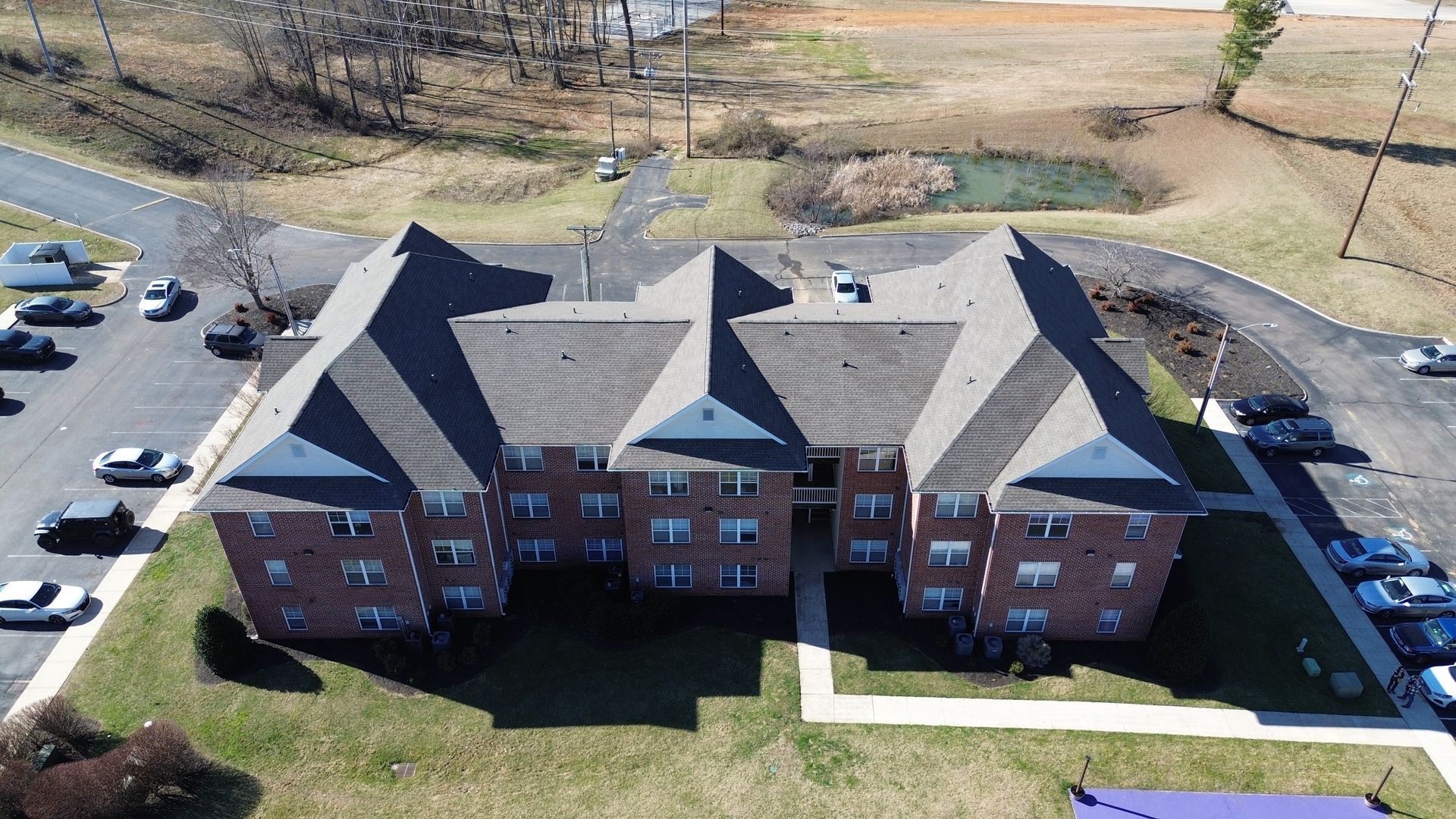 An aerial view of a large brick building with a parking lot in front of it.