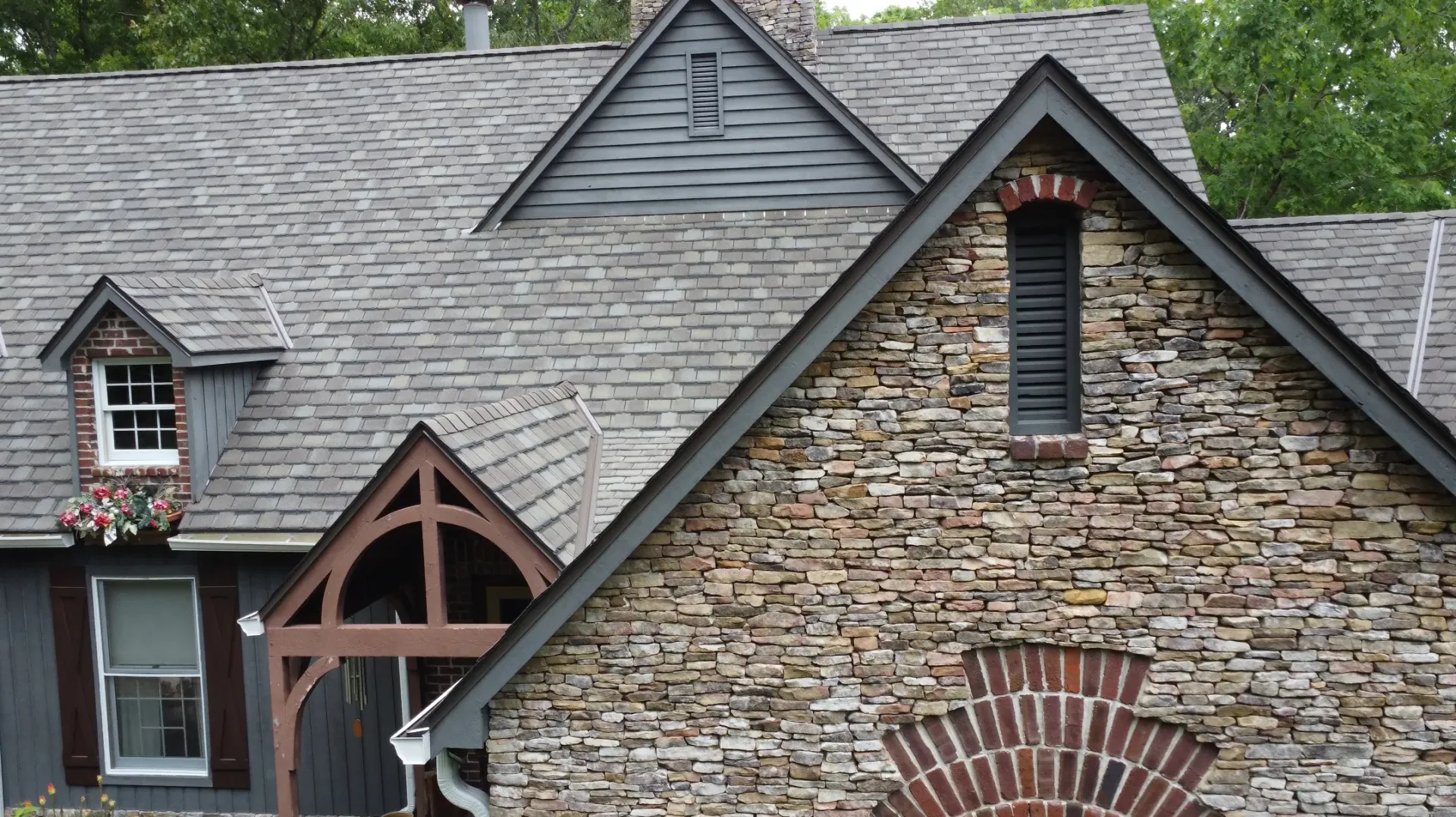 A house with a stone facade and a gray roof