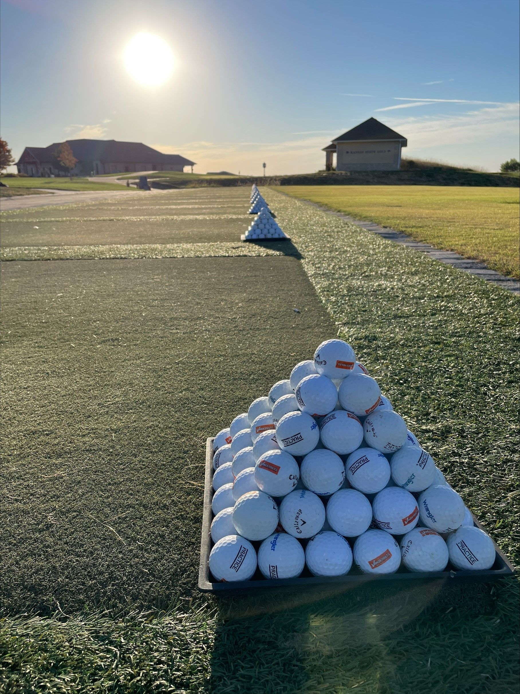 A person is holding a basket of golf balls on a golf course.