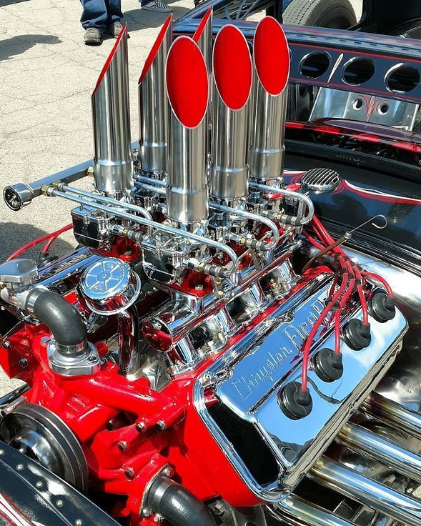 a close up of a red engine with chrome exhaust pipes