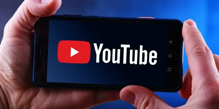 Hand holding a smartphone displaying the YouTube logo.