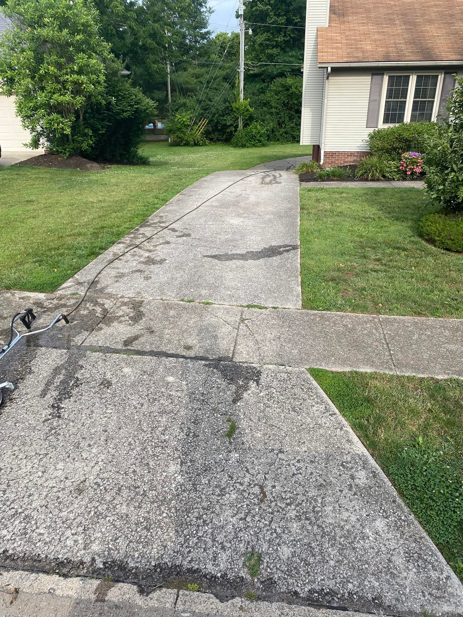 A concrete walkway leading to a house with a lot of grass.