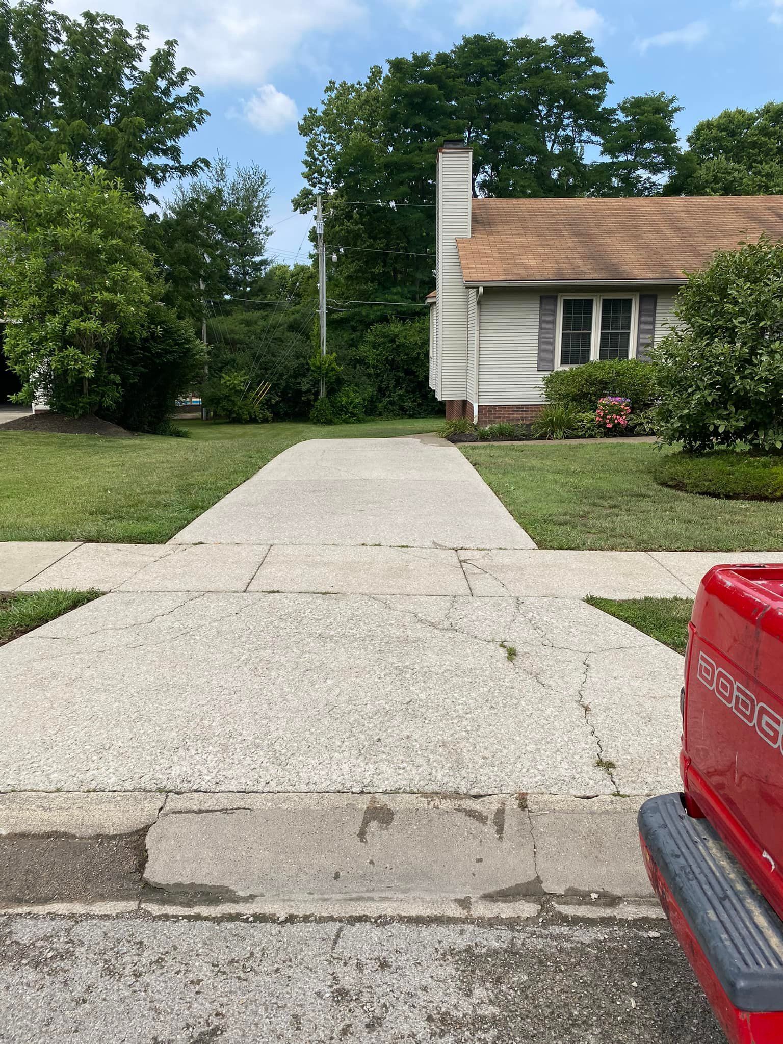 A red truck is parked on the side of the road in front of a house.