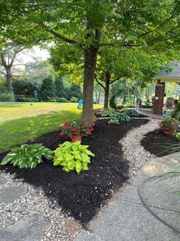 A garden with a path leading to a gazebo and a tree.
