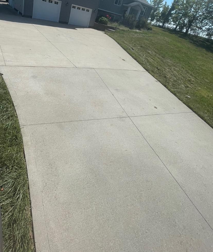 A concrete driveway leading to a house with a white garage door.