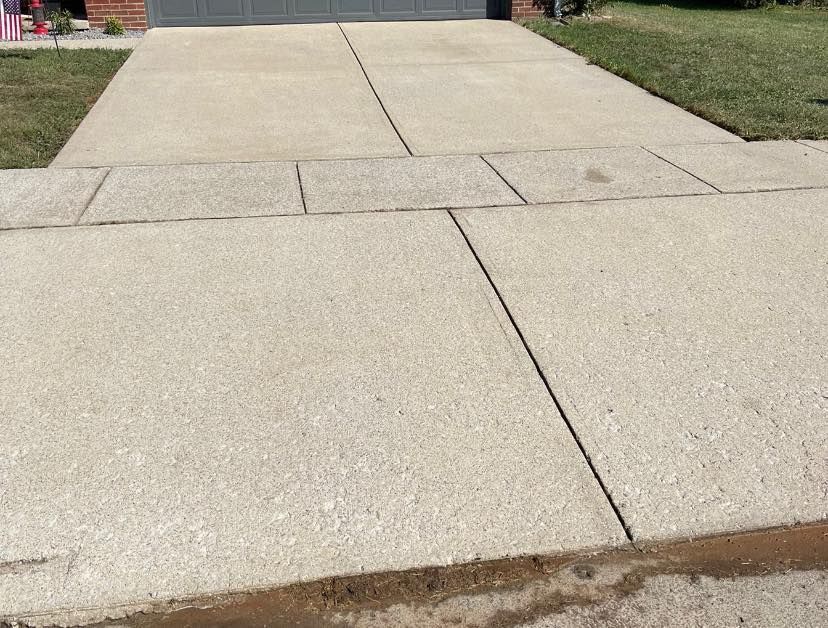 A concrete driveway leading to a garage and a house.