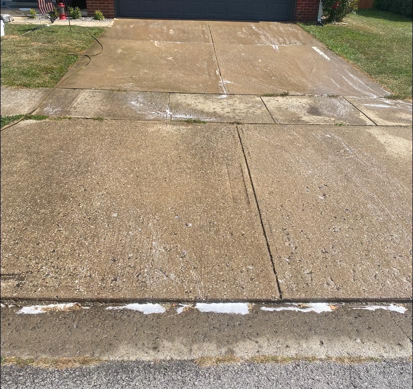 A dirty concrete driveway in front of a house.