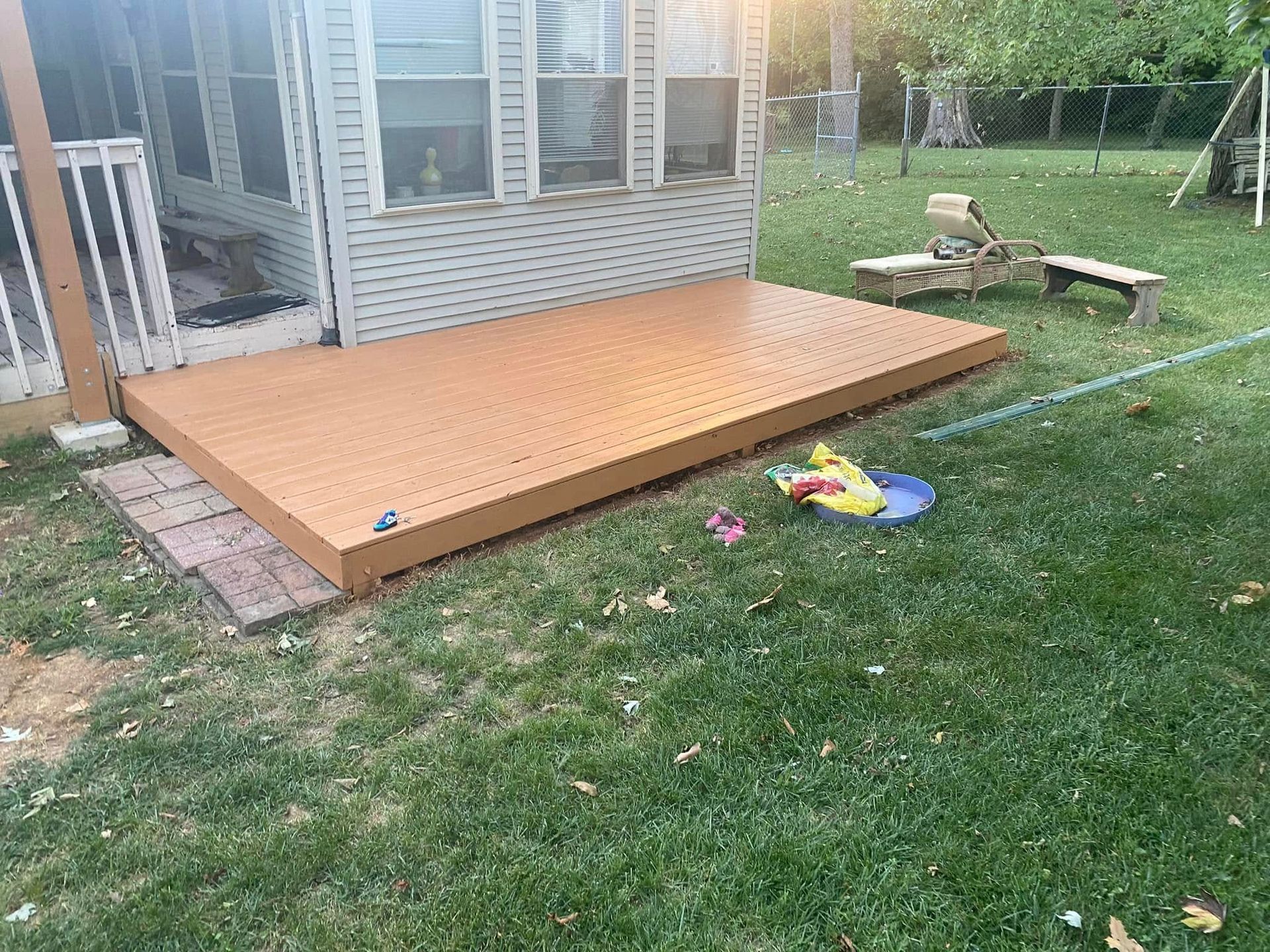 A wooden deck is sitting in the grass in front of a house.