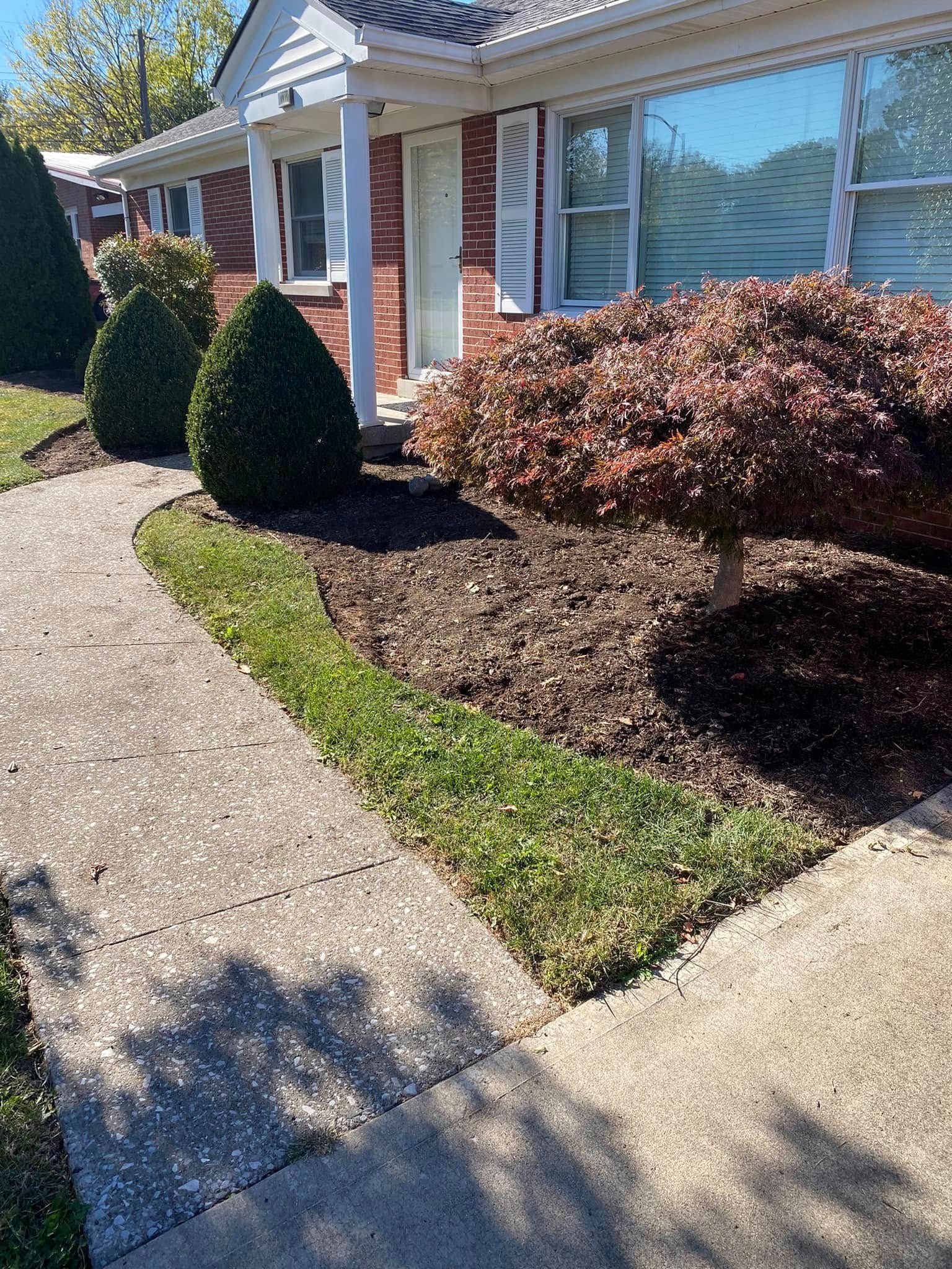 A brick house with a concrete walkway leading to it.