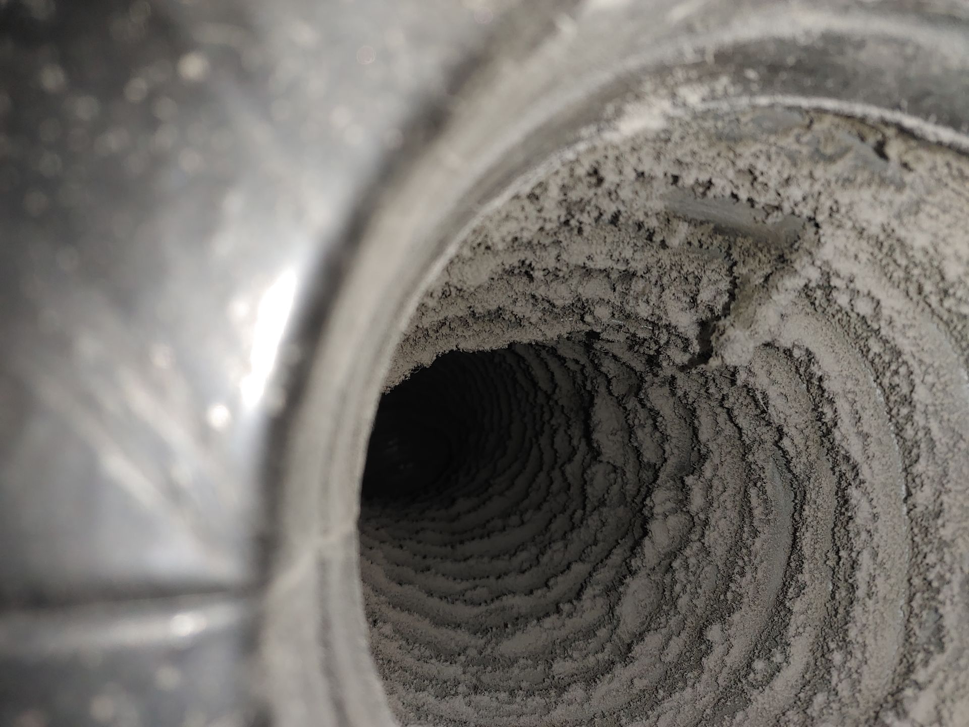 À l'intérieur d'un conduit d'aération poussiéreux, recouvert d'une épaisse couche de débris gris.