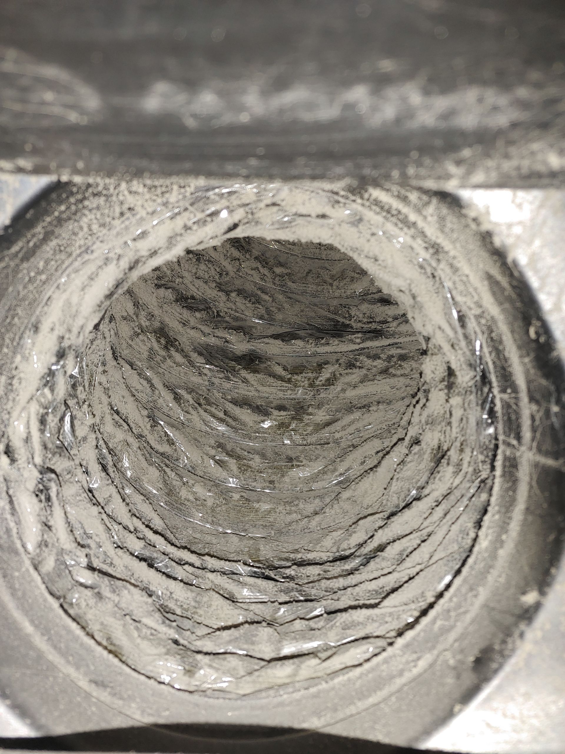 Vue intérieure d'un conduit d'air cylindrique et poussiéreux. Gris avec des surfaces texturées et superposées.