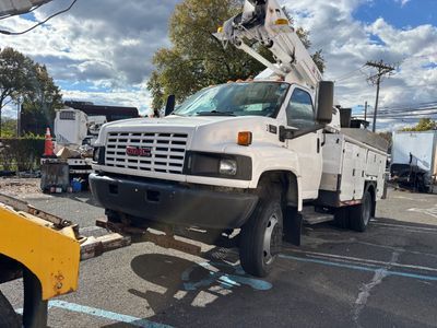 White GMC utility truck with a lift parked outdoors.