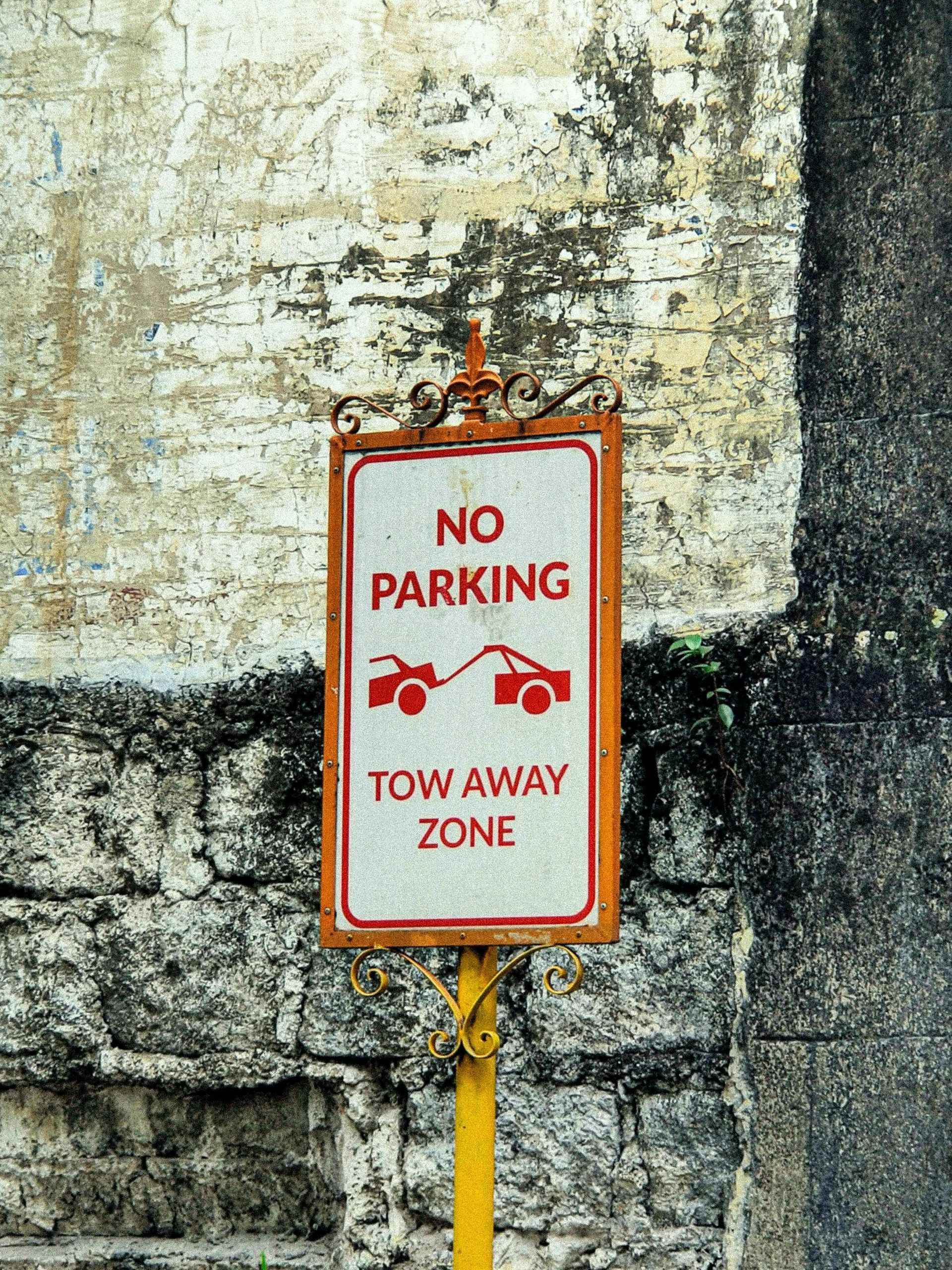 No parking sign in a tow away zone. Orange and white sign with tow truck illustration.