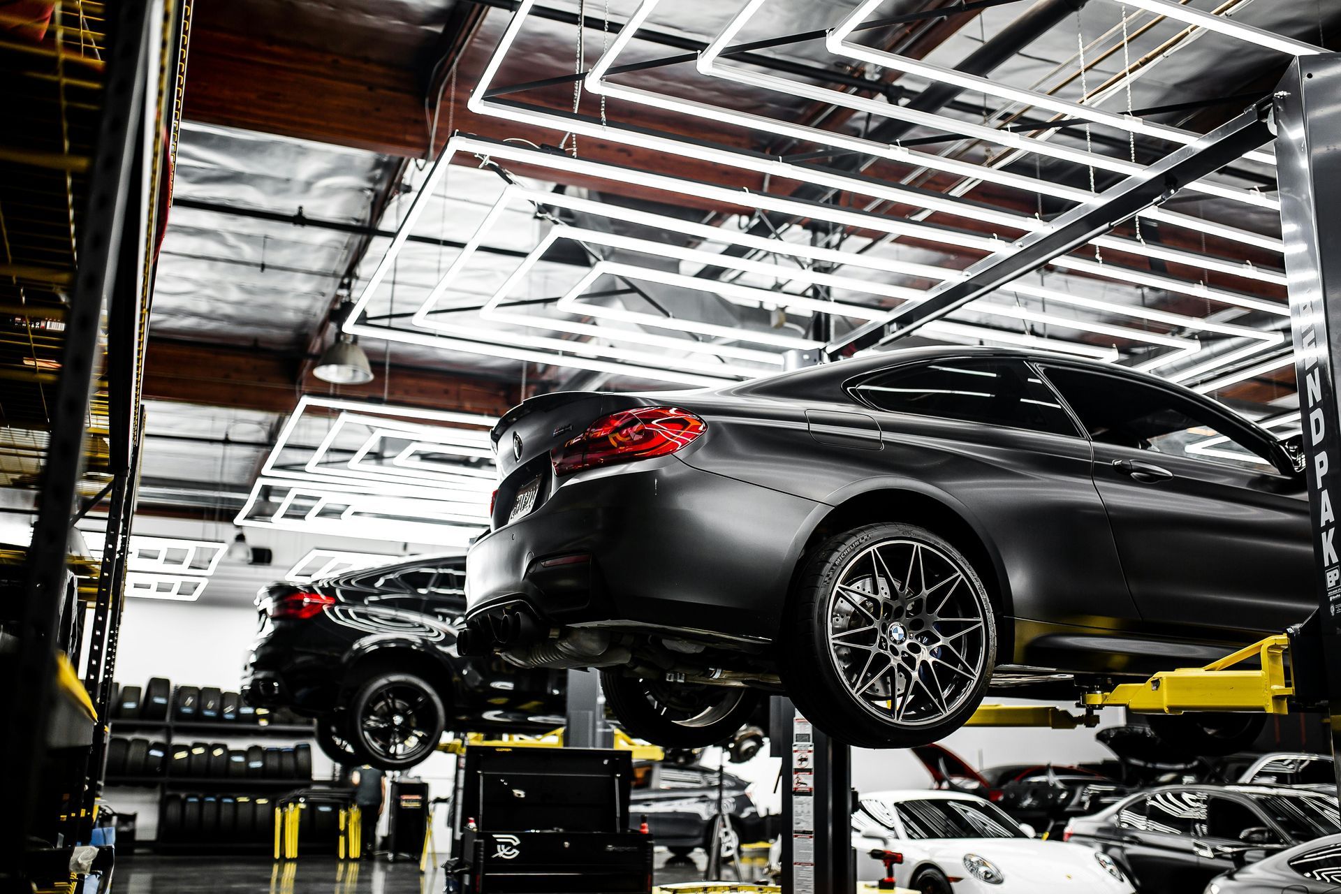 Cars on lifts in a brightly lit auto shop.