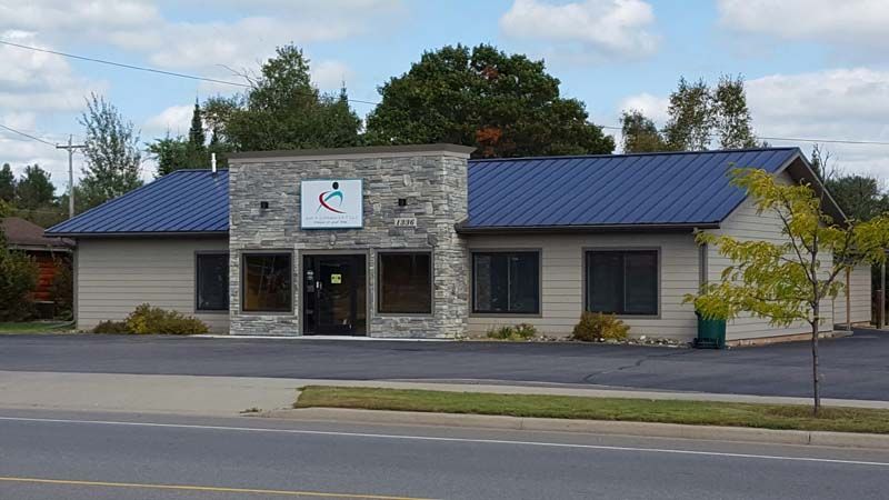 A small building with a blue roof is sitting on the side of the road.