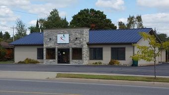 A small building with a blue roof is sitting on the side of the road.