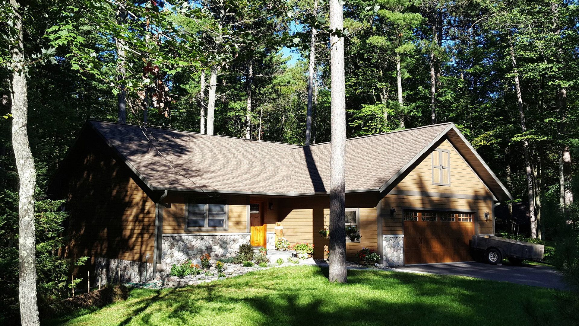 A house in the middle of a forest with a car parked in front of it