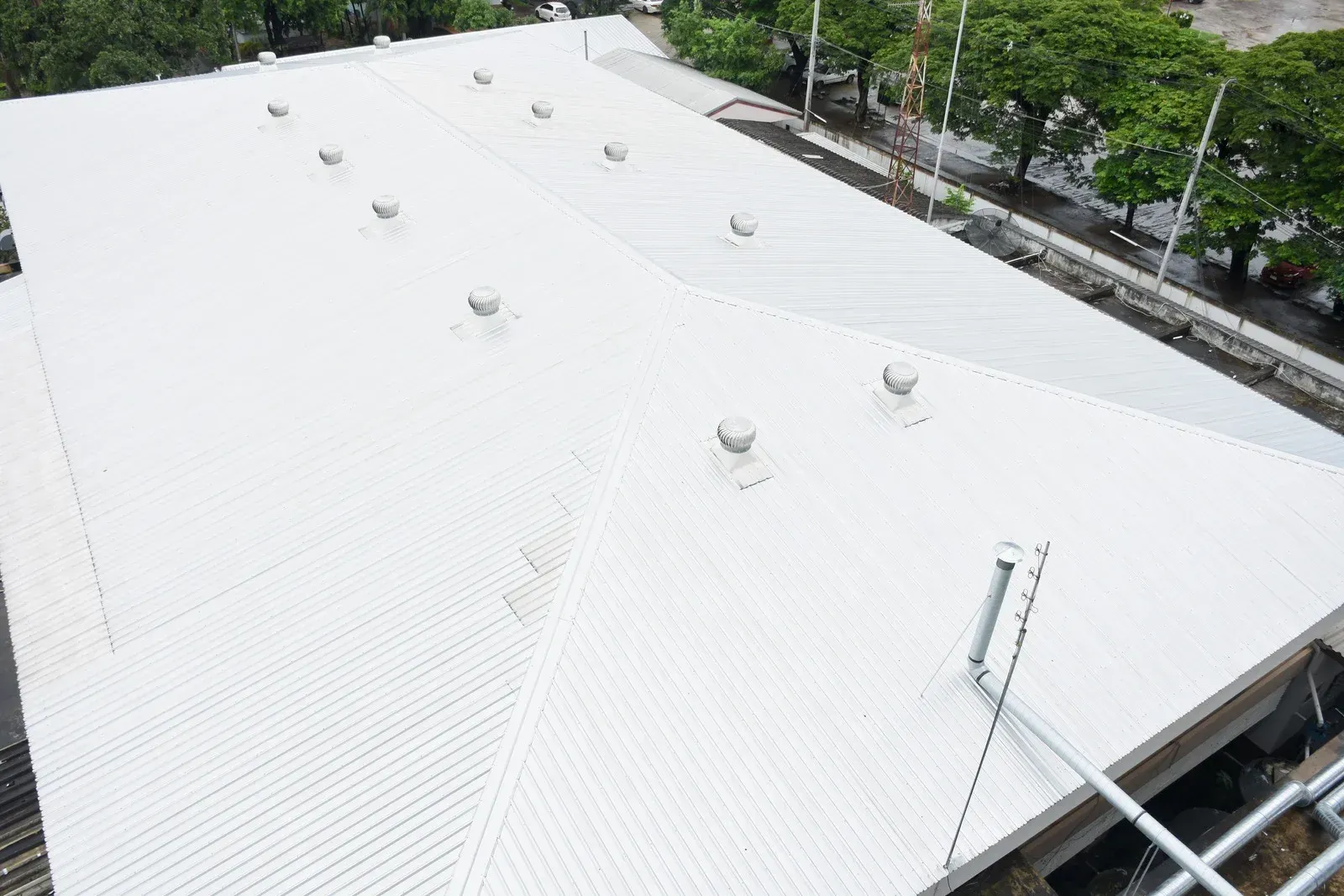 An aerial view of a large white roof with trees in the background.