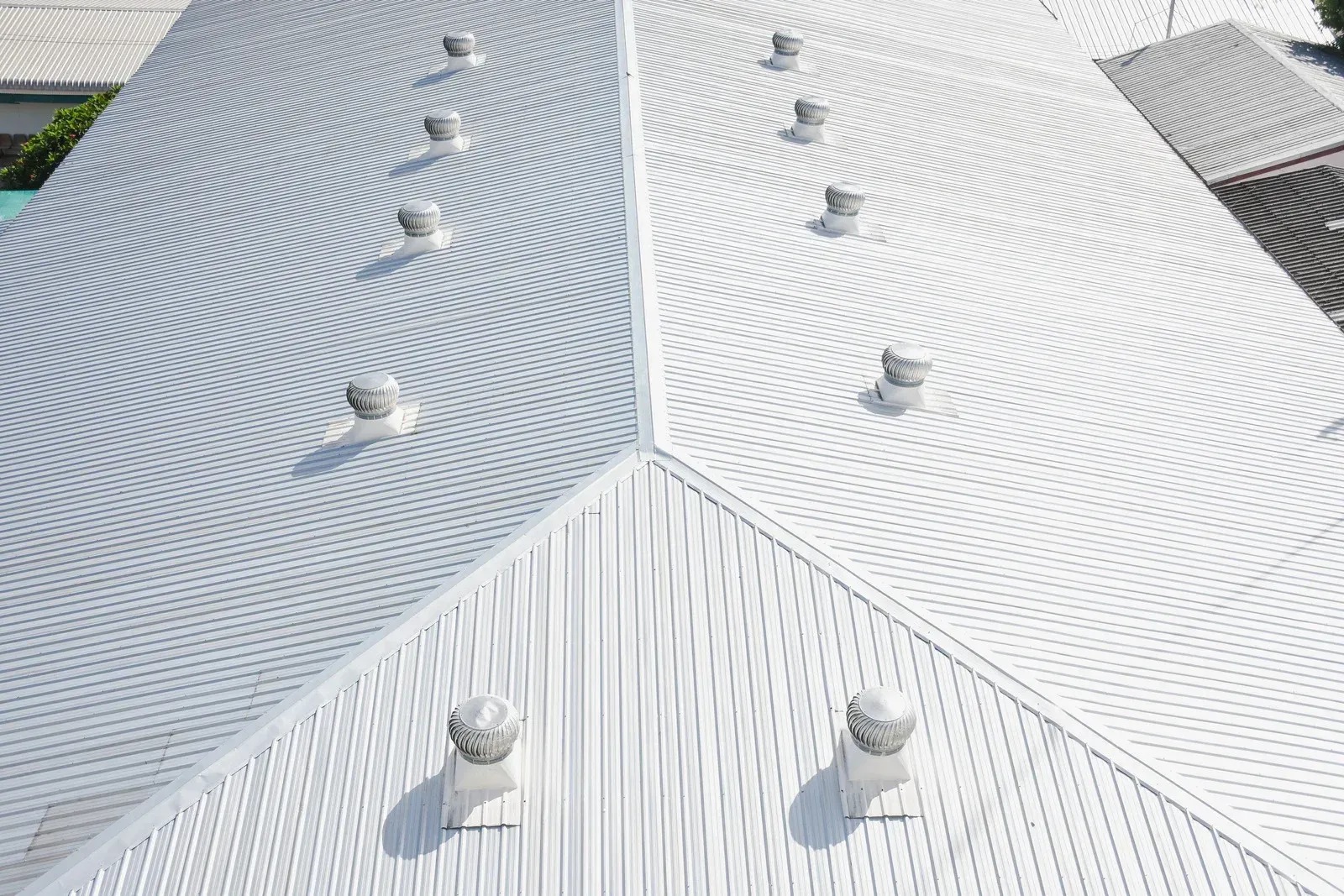 An aerial view of a white roof with a lot of vents on it.
