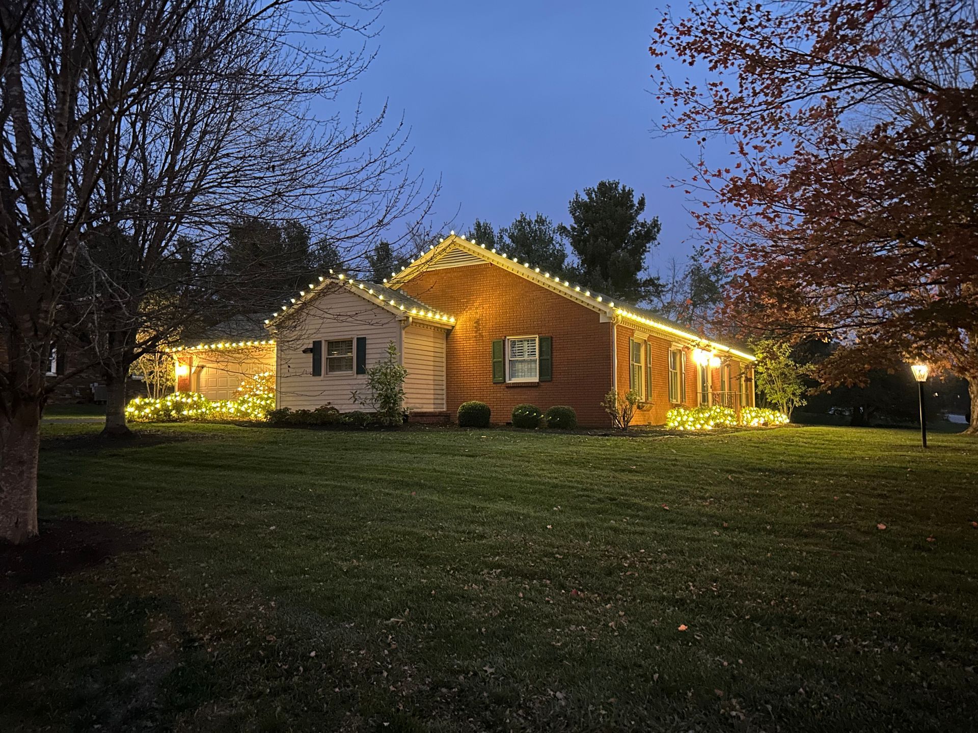 Christmas market in front of a grand building with string lights and decorations. Evening sky.