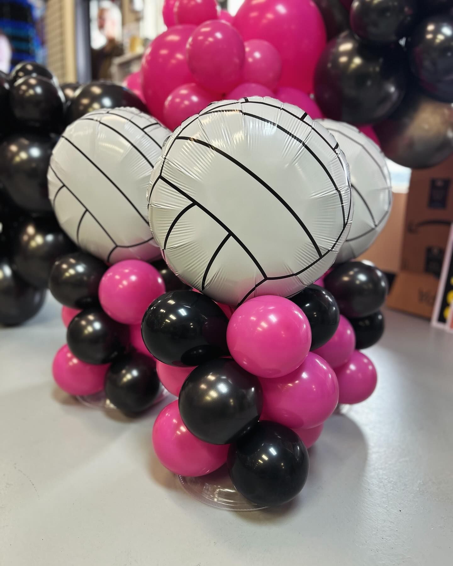 A bunch of pink and black balloons shaped like volleyballs