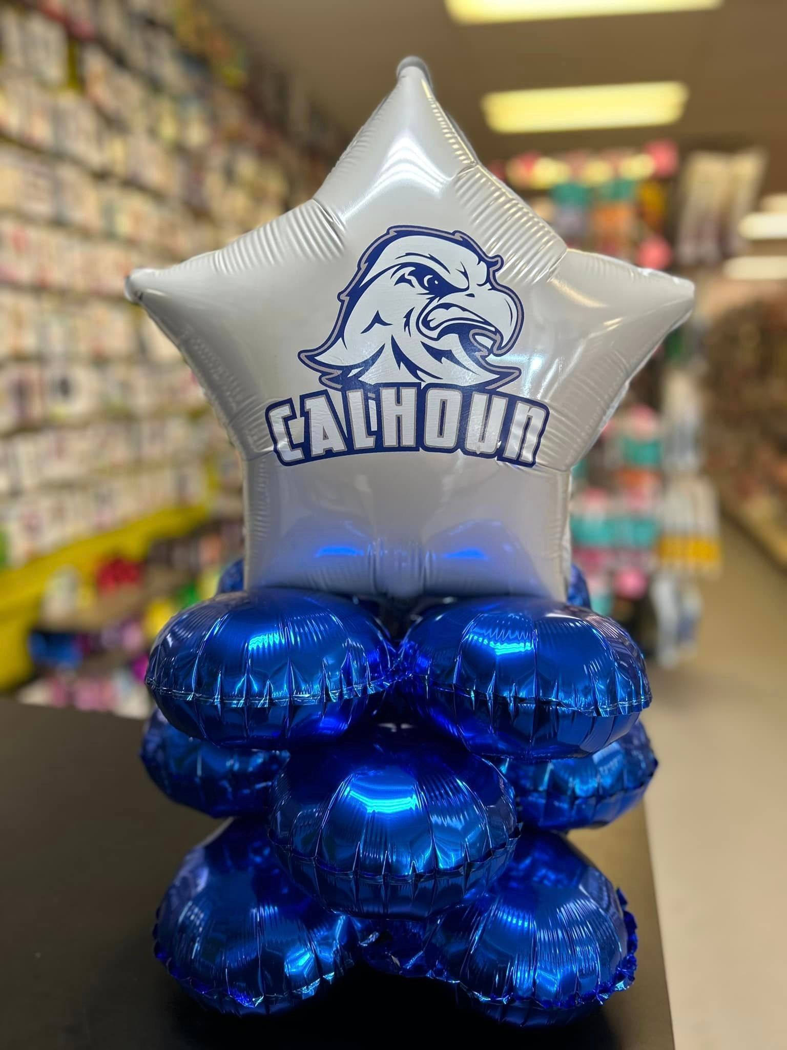 A star shaped balloon is sitting on top of a stack of blue balloons.