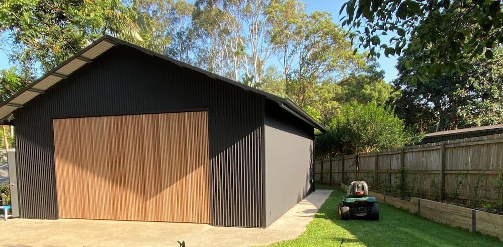 Black Shed With a Wooden Door and a Lawnmower on the Grass — Northern Rivers Sheds in South Lismore, NSW