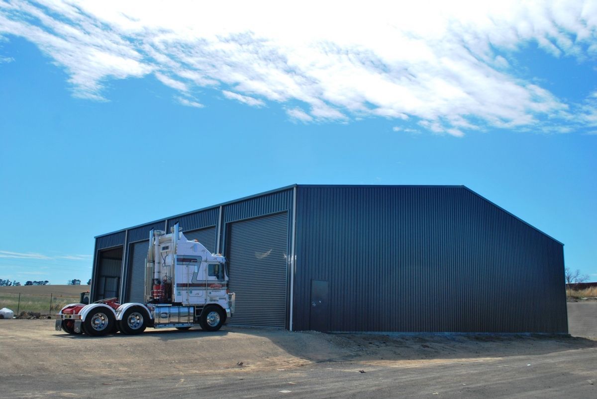 Semi-truck parked in front of a dark blue corrugated metal shed on a sunny day - Northern Rivers Sheds in South Lismore, NSW