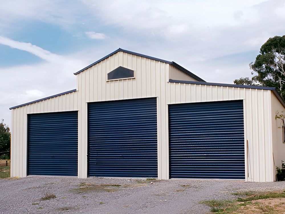 Three-bay Barn With Dark Blue Roller Doors and Beige Siding — Northern Rivers Sheds in South Lismore, NSW