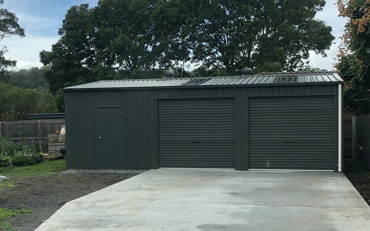 Grey metal shed with two garage doors and concrete driveway— Northern Rivers Sheds in Byron Bay, NSW