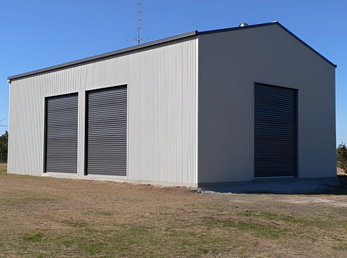 Metal Shed With Three Black Roller Doors and Gray Siding — Northern Rivers Sheds in South Lismore, NSW