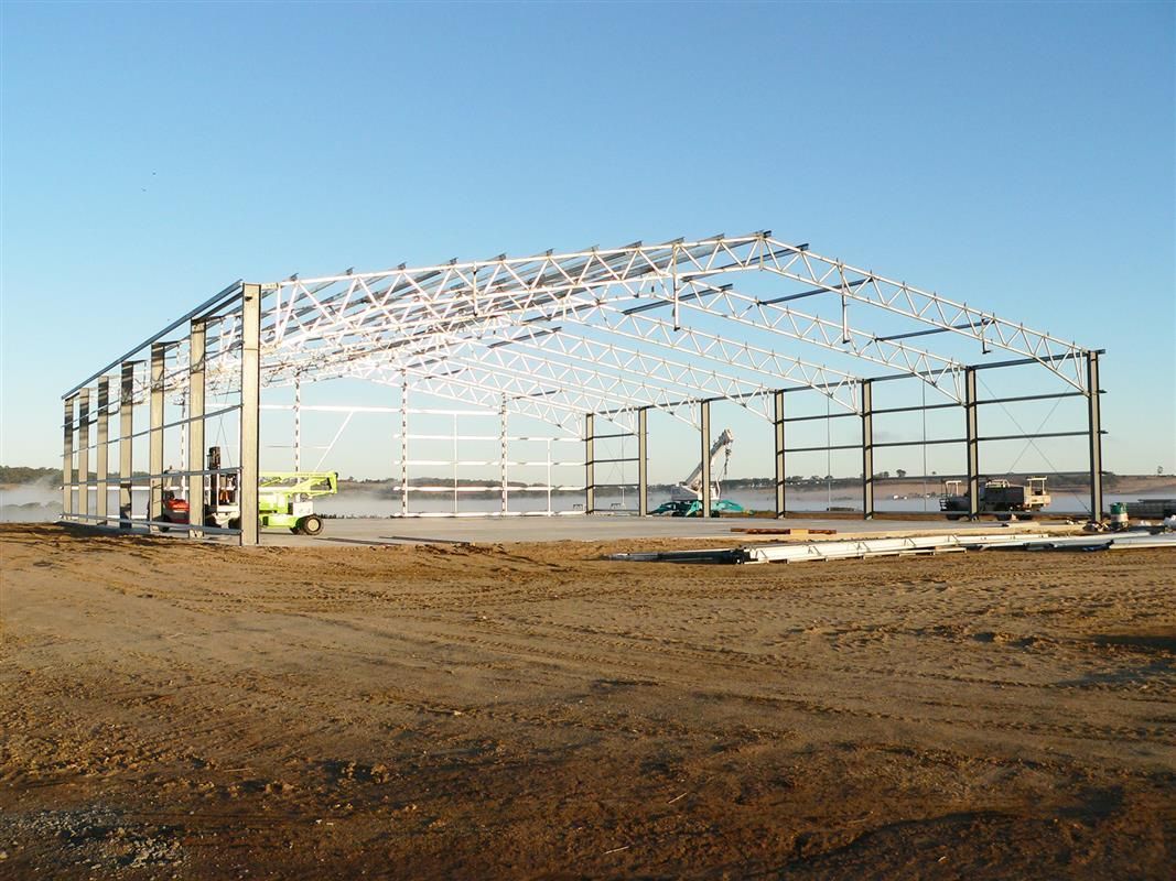 Steel frame of a large building under construction on a dirt lot, clear sky background -Northern Rivers Sheds in South Lismore, NSW