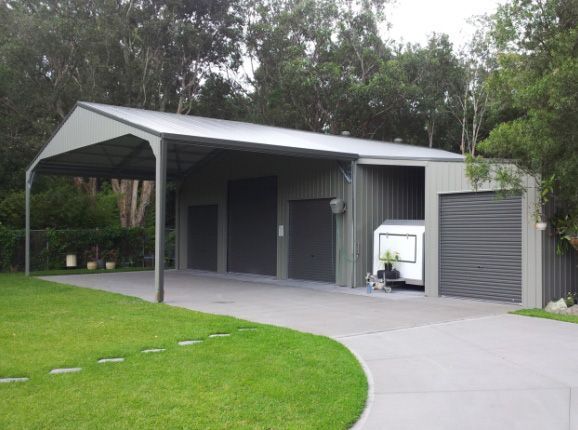 Gray Metal Shed With Carport on a Concrete Driveway, Green Lawn, and Trees — Northern River Sheds in Lismore, NSW