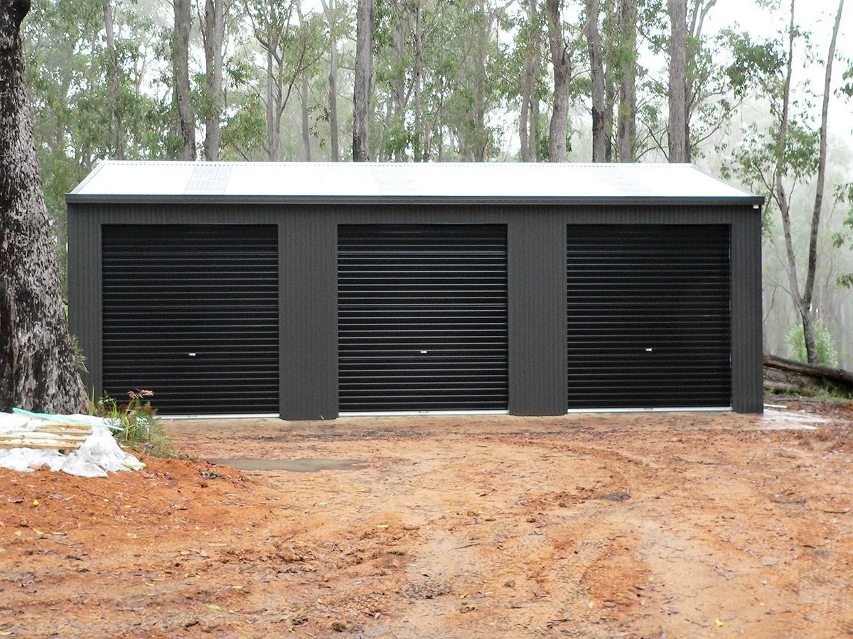 Triple-Car Garage With Dark Gray Doors in a Dirt Driveway and White Roof — Northern River Sheds in Lismore, NSW