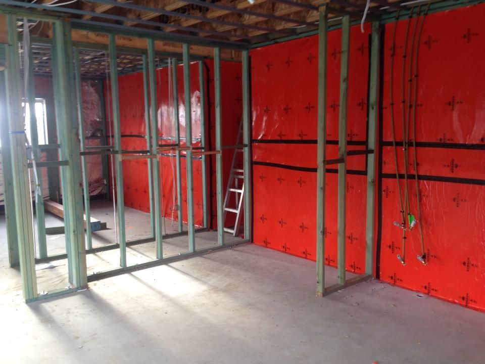Interior Framing of a Room Under Construction With Red Insulation and Exposed Studs — All Pest QLD In Sippy Downs, QLD