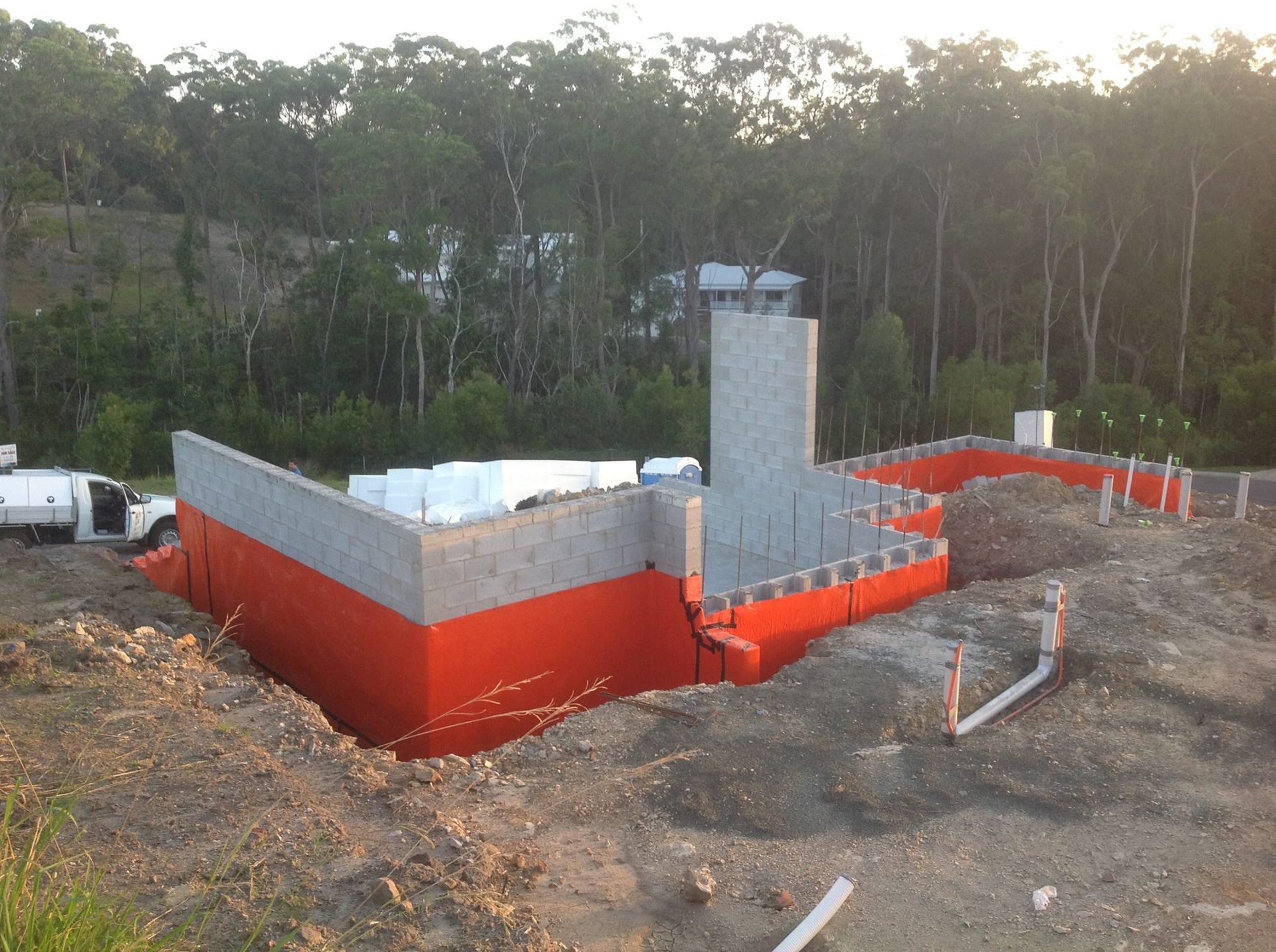 Construction Site With Block Walls in Red and Gray Against a Backdrop of Trees — All Pest QLD In Sippy Downs, QLD