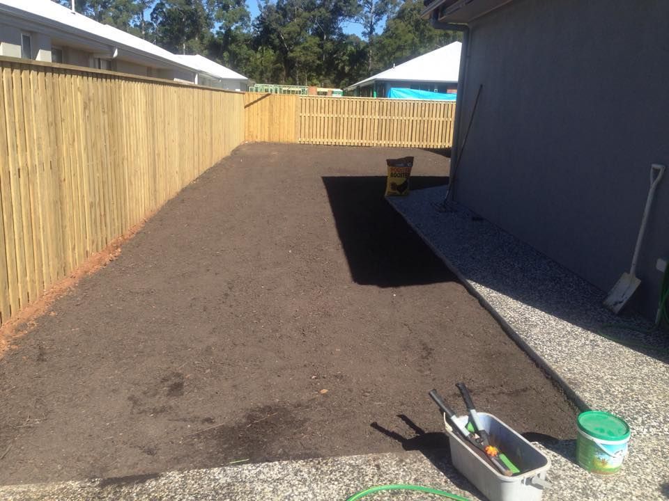 A Backyard With Fresh Soil Bordered by a Wooden Fence and a House — All Pest QLD In Noosa, QLD