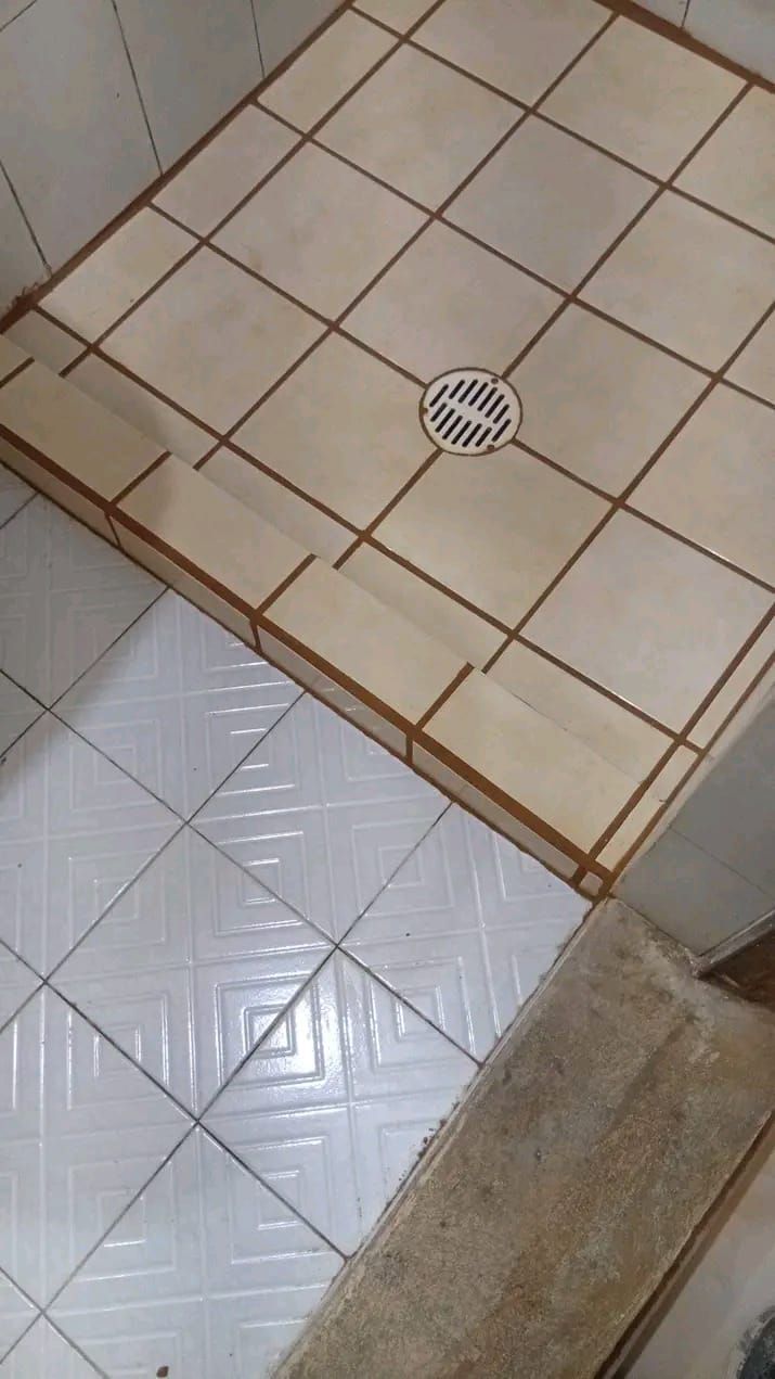 Vista aérea de un suelo de ducha alicatado con desagüe central, junto a un suelo de baño alicatado en blanco.