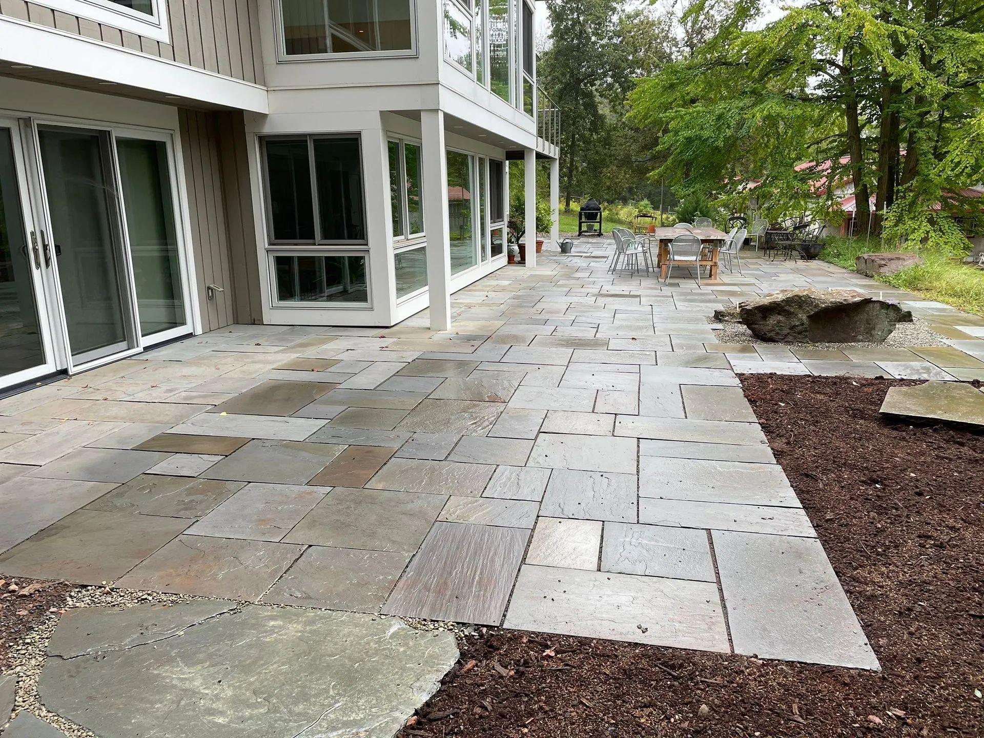 A large patio in front of a house with sliding glass doors
