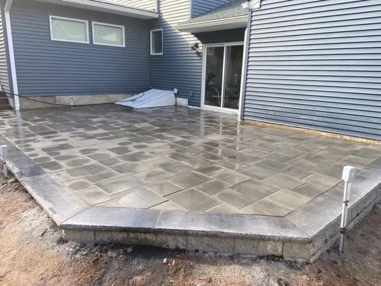 A patio is being built in front of a blue house.
