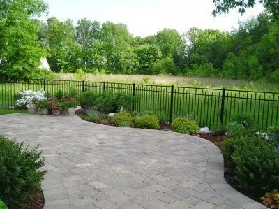 A patio with a fence surrounding it and a field in the background