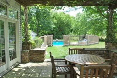 A patio with a table and chairs and a pool in the background