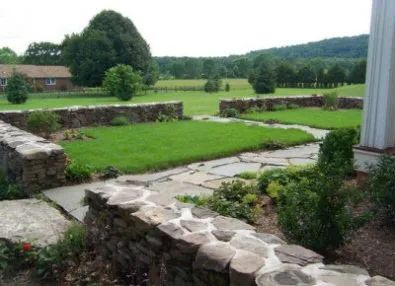 A stone walkway leading to a lush green field