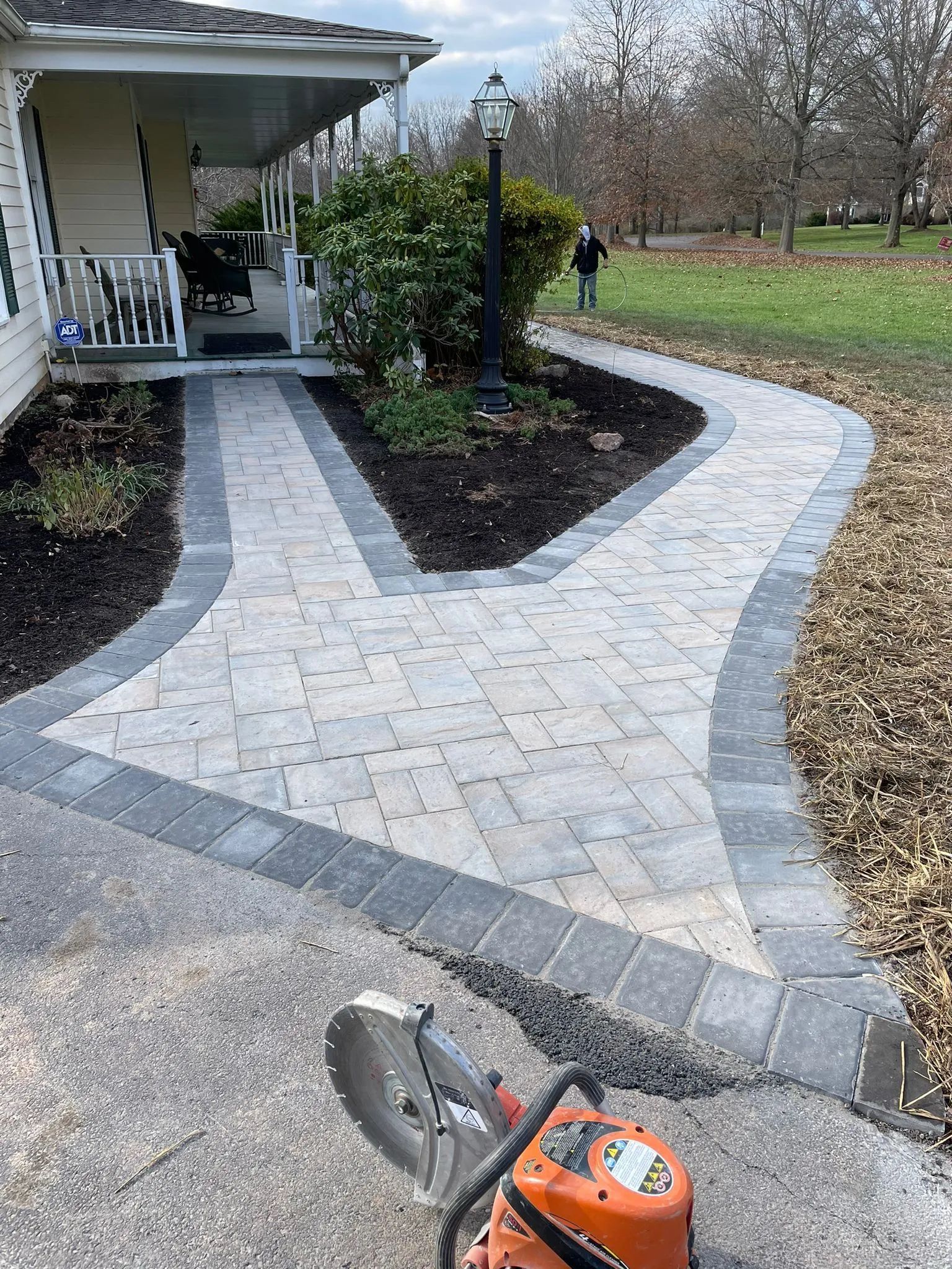A chainsaw is sitting on the sidewalk in front of a house.
