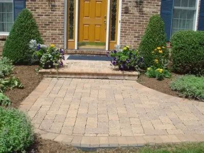 A brick house with a yellow door and a brick walkway
