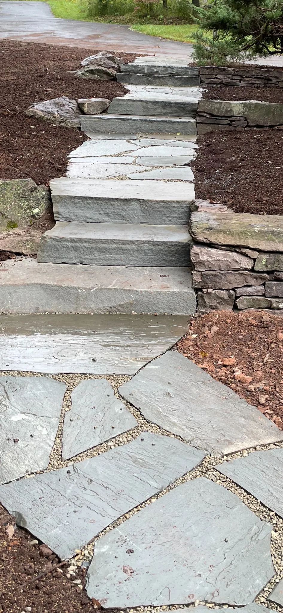A stone walkway with stairs leading up to a stone wall.