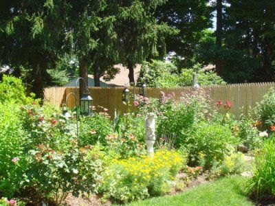 A garden with a wooden fence and lots of flowers