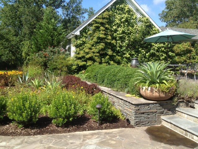 A garden with pink and white flowers in front of a house.