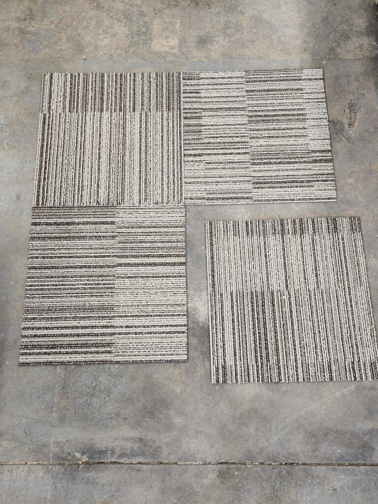 Four tiles with a striped pattern are sitting on a concrete surface.