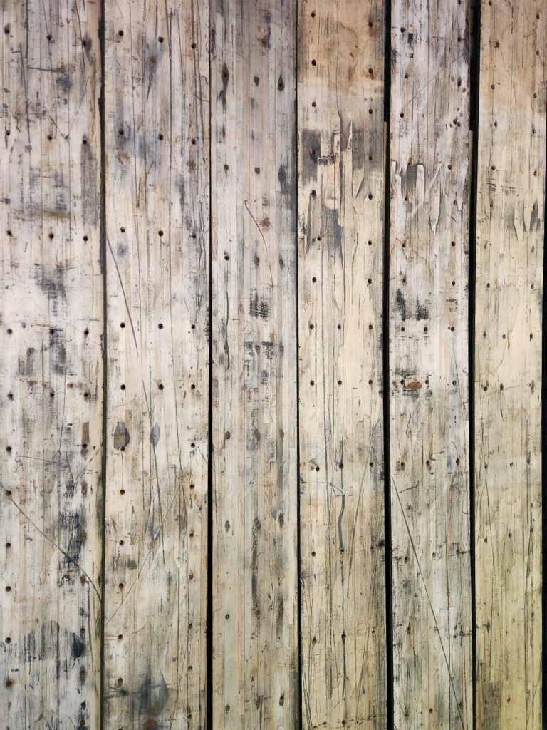 A close up of a wooden wall with a lot of holes in it.